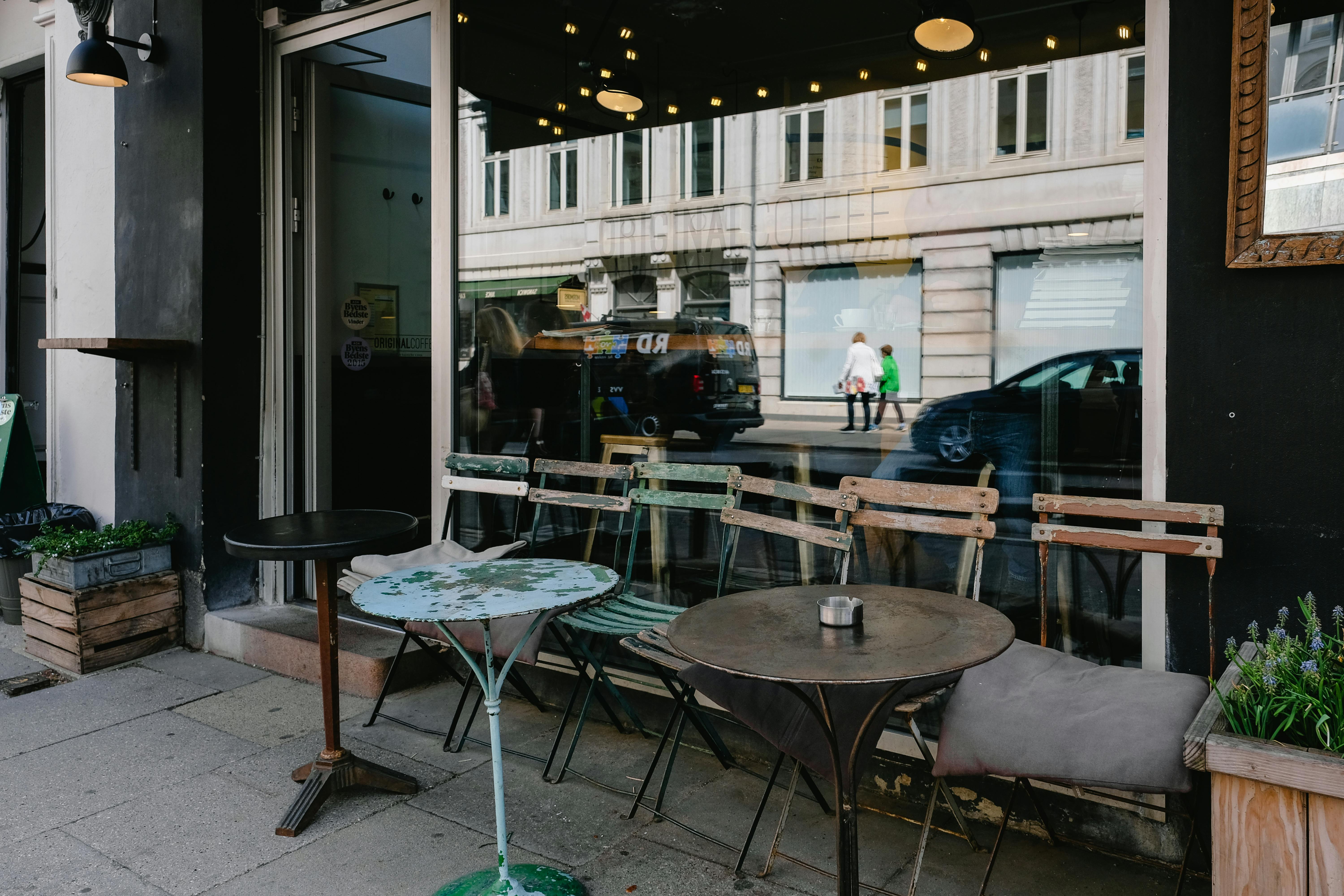 Street-side cafe storefront with outdoor tables and chairs.